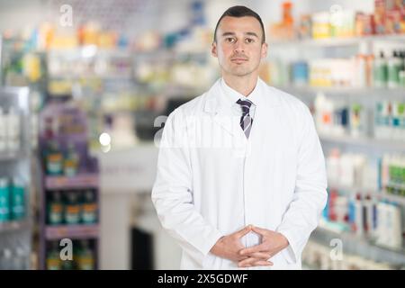 Young male pharmacist posing in chemist's shop with large assortment Stock Photo