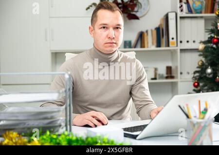 Man office worker using laptop during Christmastime Stock Photo