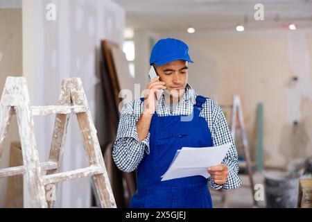 Young foreman with documents in his hands is talking on a mobile phone Stock Photo