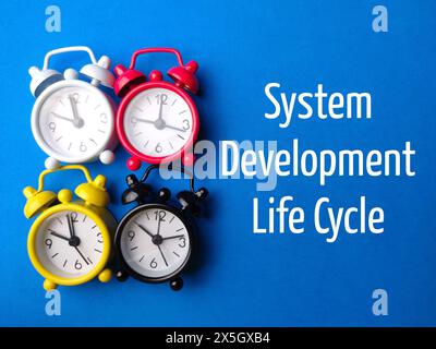 Top view clock with text System Development Life Cycle on blue background. Stock Photo