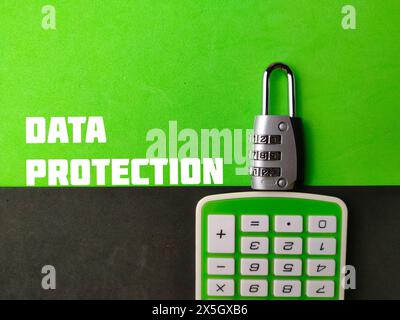 Top view padlock and calculator with text DATA PROTECTION on green and black background. Stock Photo