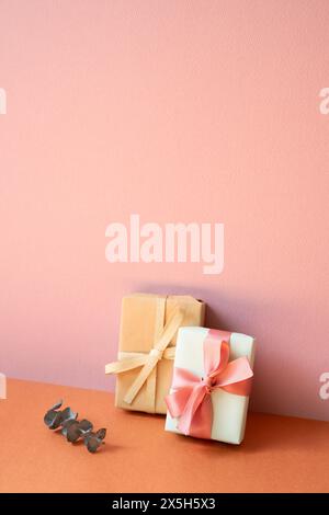 Gift boxes and eucalyptus leaf on orange table. pink wall background with copy space Stock Photo