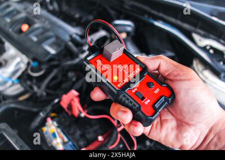 Car relay testing with a relay tester , relay tester in a mechanic hand for system test , Car maintenance and repair servicing concept Stock Photo