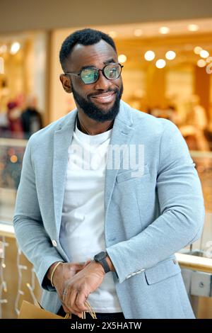 handsome bearded man in stylish suit, jacket, watch standing at shopping mall. time for sales, black friday, buying, purchase Stock Photo