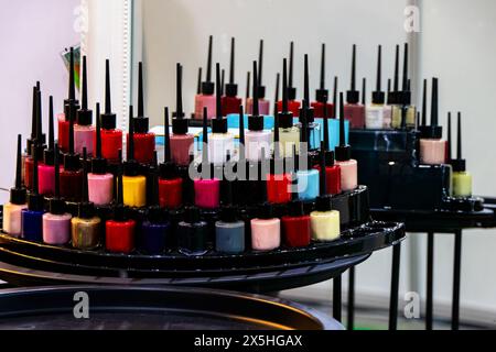 Assorted nail polish bottles in various colors neatly arranged on salon shelves Stock Photo