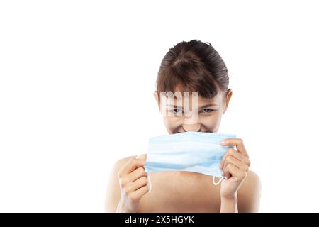 Portait of a happy girl smiling and wearing medical face mask against viruses pollution or dust. Looking at camera. Stock Photo