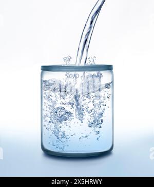 Water jet splashing into a glass jar against white and blue color Stock Photo