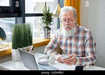 Shocked senior caucasian retired man looking atsmartphone screen with interest, getting bad news, reading online chat message, email letter. modern technologies and retired people concept Stock Photo