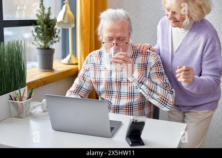 Old spouses using apps on laptop. Happy elderly couple having fun online, surfing the Net. Senior people active social networks users spend time together, watching something interesting Stock Photo