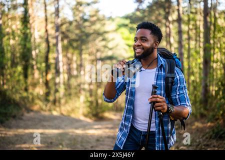Young man enjoys using binoculars and hiking in nature. Stock Photo