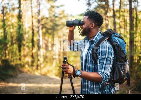 Young man enjoys using binoculars and hiking in nature. Stock Photo