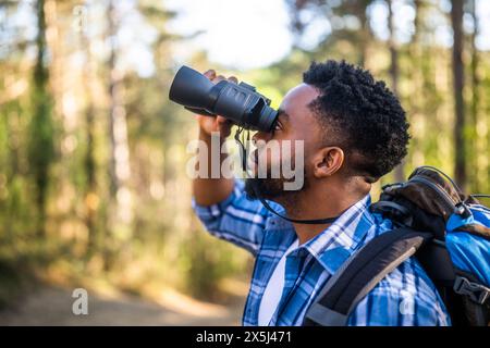 Young man enjoys using binoculars and hiking in nature. Stock Photo