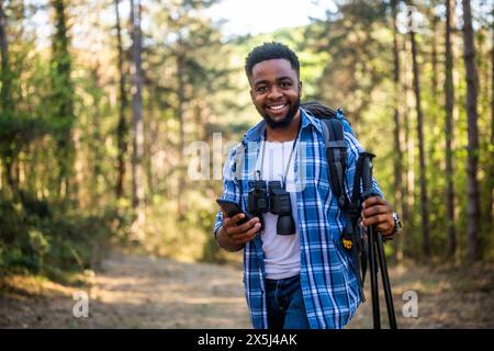Young man enjoys hiking and using mobile phone in nature. Stock Photo