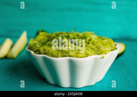 Grated zucchini mix in a white bowl, teal background! Stock Photo