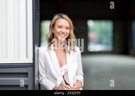 Woman smiling in white suit standing in warehouse building Stock Photo