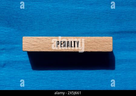 Penalty word written on wooden block with blue background. Conceptual penalty symbol. Copy space. Stock Photo