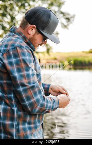 Angler attentively baiting hook by the lake. Stock Photo