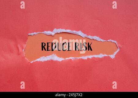 Reduce risk words written on torn paper with orange background. Conceptual reduce risk symbol. Copy space. Stock Photo