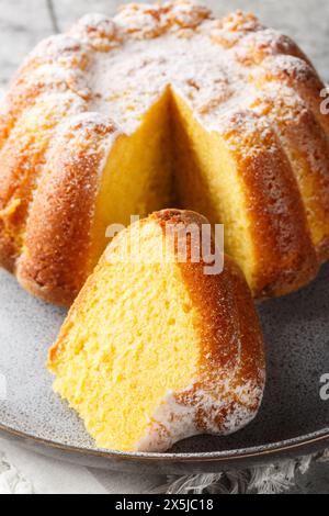 Close-up of Meskouta orange pound cake with powdered sugar on a plate on the table. Vertical Stock Photo