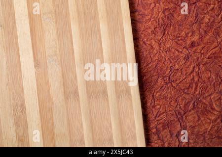 Wooden cutting board on brown paper abstract background. Top view. Copy space. Stock Photo