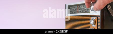 Authentic 70s radio receiver. Front view. On pink background. banner Stock Photo