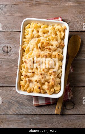 Traditional southern Mac and cheese with breadcrumbs on wooden background, top view. Homemade cheesy and creamy pasta casserole with meat. Stock Photo