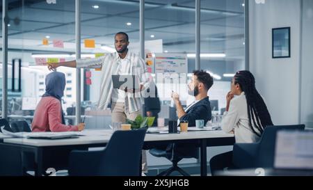 Diverse Modern Office: Successful Motivated Black Businessman Leads Meeting, talks of Company Growth. Digital Entrepreneurs Work on e-Commerce Project. Young Multi-Ethnic Creatives Brainstorm Strategy Stock Photo