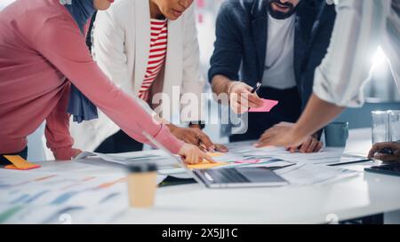 Multi-Ethnic Office Conference Room Businesspeople Meeting at Big Table. Diverse Team of Creative Entrepreneurs Talk, Use Laptop. Specialists work in Digital e-Commerce Startup. Focus on Hands Stock Photo