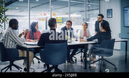 Multi-Ethnic Office Conference Room Meeting: Diverse Team of Young Entrepreneurs, Specialists Talk, Use TV for infographics. Smiling Businesspeople Discuss Investment Strategy in e-commerce Startup Stock Photo