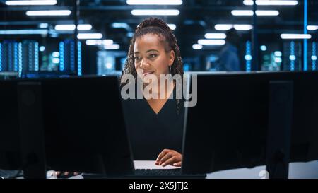 Successful African American Businesswoman Working on Computer in Big City Office Late in the Evening. Female Executive Director Managing Digital e-Commerce Project, Finance Analysis Stock Photo