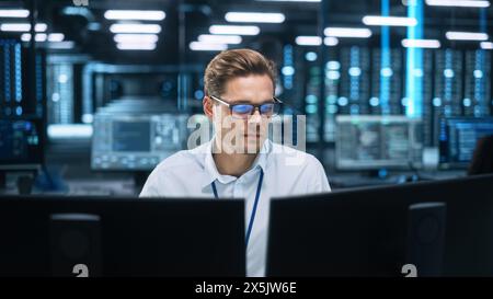 Night Office: Young Caucasian Man Working on Two Desktop Computers. Digital Entrepreneur Typing Code, Creating Modern Software, e-Commerce App Design, e-Business Programming Stock Photo