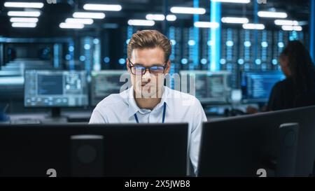 Focused System Administrator or Consultant Look at the Screen and Saves Backup Data in Dark Evening Room Workplace Station Indoors. Network Technologies Concept Stock Photo