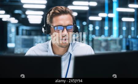 Customer Service Operator at Work in Call Center. Caucasian Call Center Worker Talking with Customer in Modern Office at Night. Worker Speaking on Video Call on Computer Sitting at Table at Office Stock Photo