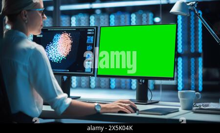 Night Office: Young Caucasian Woman Working on Green Screen Chroma Key Desktop Computer. Programmer Typing Code, Creating Modern Software, e-Commerce App Design. Over Shoulder Stock Photo