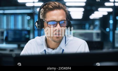 Concentrated Male Customer Support Agent Receptionist wear Headset Consult Online Client Looking at Computer Screen, Helpline Operator Secretary Make Conference Video Call Stock Photo