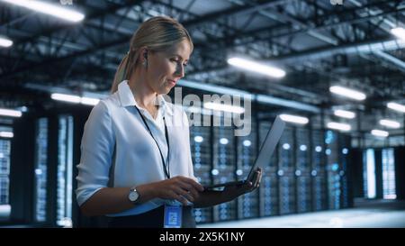 High-Speed Data Transfer and Smooth Server Operation. Female Engineer Programs Something and Looking at Laptop Computer while Works in Dark Modern High-Tech Office. Analytics and Statistics Concept Stock Photo
