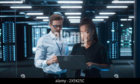 Mature Businesswoman Listens to Professional Advisor in Her Office, They Discuss Data Show on a Laptop. Smart Businesspeople Working in Finance. Specialists Work in Diverse Team. Big Data Concept Stock Photo