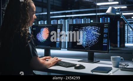 Hi-Tech AI Research Center African American Female IT Engineer Working on a Neural Network Project, She Uses Two Personal Computer, Screen Shows Big Data Graphics, Futuristic Machine Learning Concept Stock Photo