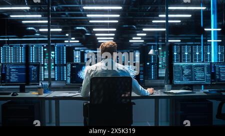 Back View of the Male Computer Engineer and Scientist Create Neural Network. In Office Displays Showing 3D Simulation of Big Data, Machine Learning Processes, Web3 Programming Concepts Stock Photo