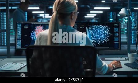 Futuristic Concept: Female Computer Engineer Looking on the Two Displays while Working on the Computer. Screen Shows Interactive Neural Network, Artificial Intelligence Project, User Interface Stock Photo
