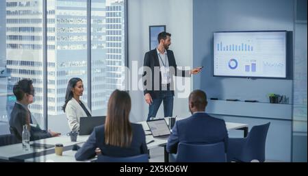 Office Conference Room Meeting: Digital Enterpreneur Presents e-Commerce Investment Strategy for Group of Investors. Wall TV Showing Big Data Analysis, Infographics, Stock Market Information, Trends Stock Photo