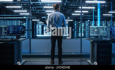High-Tech Startup Concept: Innovative Male Software Engineer Standing, Doing Big Data Analysis near the Monitors Showing Programming Code. Developing Futuristic e-Commerce App with Machine Learning. Stock Photo