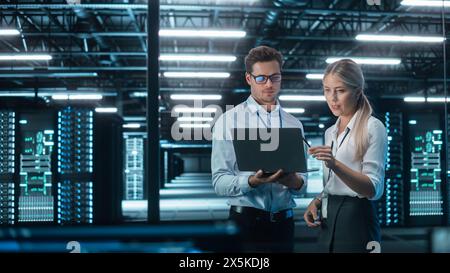 Male and Female Programmers Talking about Work, Solving Problems Together, Using Laptop Computer. Software Development / Code Writing / Website Design / Database Architecture Concept Stock Photo
