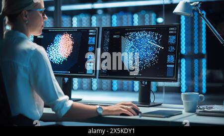 Female Technical Operator Works at Her Workstation with Multiple Displays Showing Neural Network In the System Control Room. IT Technician Works on Artificial Intelligence, Big Data Mining Project. Stock Photo