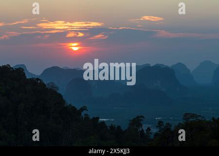 Beautiful landscape of limestone karst mountain range, dark silhouette of trees and beautiful sky during sunset in Krabi, Thailand. Stock Photo