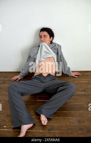 nervous scared man with sweater on his mouth, drunk guy lying on the floor, hangover, psychological illness , full length photo Stock Photo