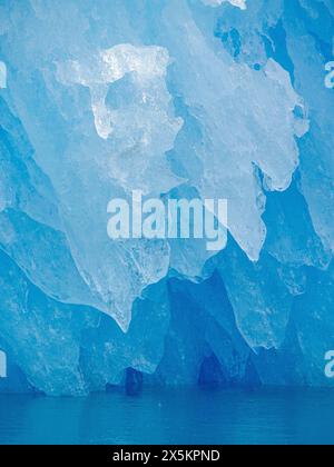 Iceberg in the fjord with melt structure. landscape in the Johan Petersen Fjord, a branch of the Sermilik Icefjord, Ammassalik region, Greenland, Danish Territory. Stock Photo