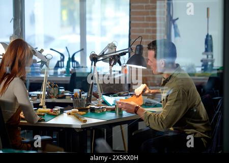 young active craftsman and craftswoman working in the workshop, behind glass wall.hobby, lifestyle. job, profession. Stock Photo