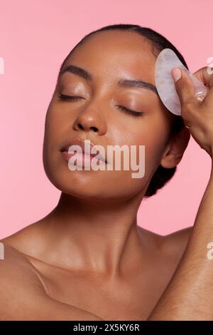 Young woman using face massager Stock Photo