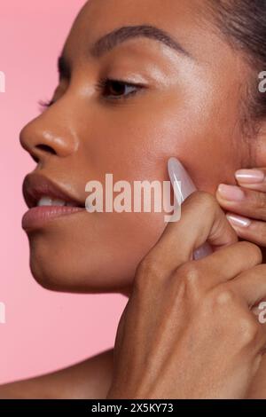 Young woman using face massager Stock Photo